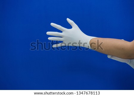 doctor pulling on white surgical gloves.blue background and Selective focus