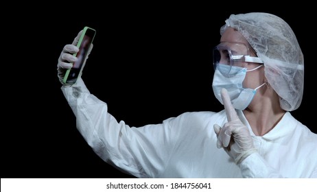 Doctor Pulls Out A Smartphone And Takes A Selfie On A Black Background