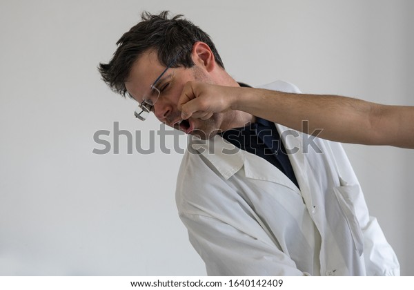 Doctor punched in the face.\
Concept of violence and aggression on doctors and healthcare\
professionals