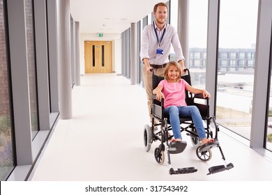 Doctor Pushing Girl In Wheelchair Along Corridor - Powered by Shutterstock