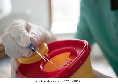 Doctor put syringe in red disposal boxes - Shutterstock ID 1218289195