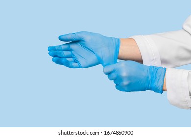 The Doctor Puts On Sterile Gloves On A Blue Background. Infection Control Concept. Danger