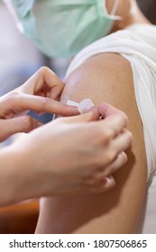 Doctor Putting Adhesive Bandage On Young Man's Arm After Injection 