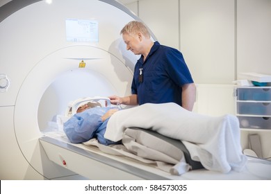 Doctor Putting Coil On Patient's Head Undergoing MRI Scan