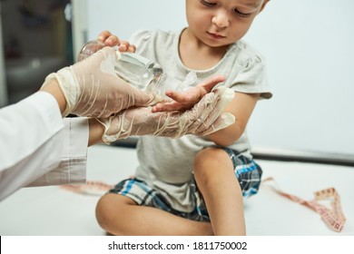 Doctor Putting Hand Sanitizer To Baby Hands. Teaching A Baby Boy Hand Washing And Hygiene. Physical Examination Of The 1-year-old Baby Boy. Well-baby Exam