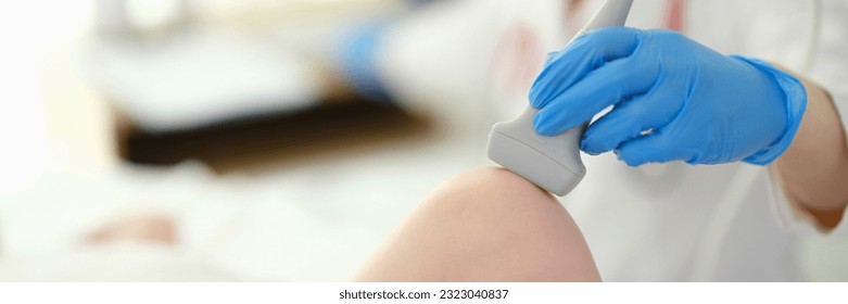 Doctor putting ultrasound probe on child knee in clinic closeup - Powered by Shutterstock