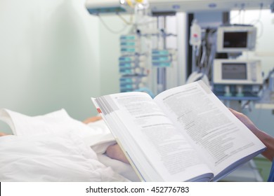 Doctor Reading Book At The Patient Bedside.