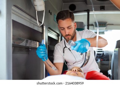 Doctor is ready for endotracheal intubation for non breathing patient. Young female paramedic holding iv solution. EMS Paramedics Provide Medical Help to an Injured Patient on the Way to a Hospital