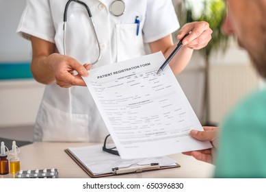 Doctor Receiving Patient Registration Form In Hospital