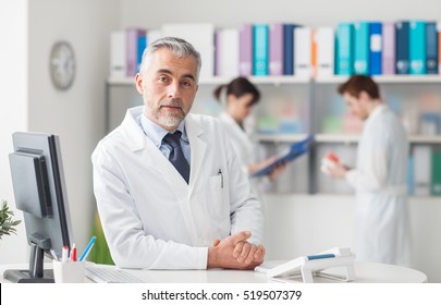 Doctor at the reception desk looking at camera, healthcare concept