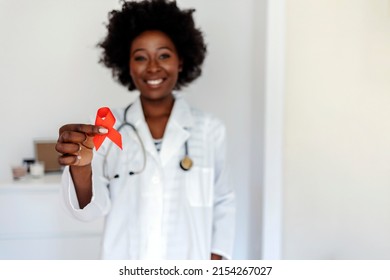 Doctor with red ribbon. Cancer concept. Doctor holds red ribbon to awareness world aids day December 1. Symbol of awareness, charity, support in disease, illness. Doctor holding a red ribbon in hands, - Powered by Shutterstock