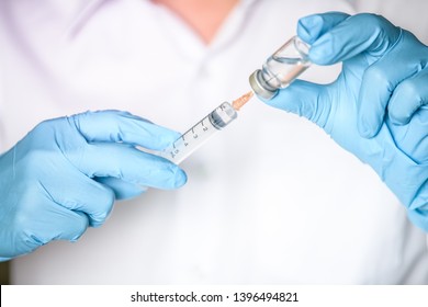 Doctor, researcher or scientist hand in blue glove holding flu, measles, rubella or hpv vaccine and  syringe with needle vaccination for baby, child, woman or man shot, medicine vial dose injection