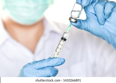 Doctor, researcher or scientist hand in blue glove holding flu, measles, rubella or hpv vaccine and  syringe with needle vaccination for baby, child, woman or man shot, medicine vial dose injection