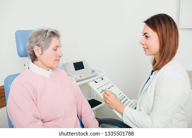 Doctor Reviewing Medical Chart With Her Senior Patient At Medical Room