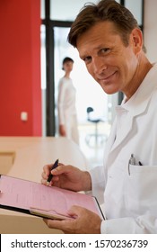 Doctor Reviewing Paperwork In Doctor's Office