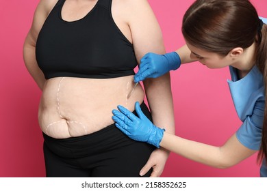 Doctor With Scalpel Near Obese Woman On Pink Background. Weight Loss Surgery