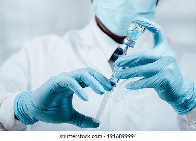 A Doctor Or Scientist In The COVID-19 Medical Vaccine Research And Development Laboratory Holds A Syringe With A Liquid Vaccine To Study And Analyze Antibody Samples For The Patient.
