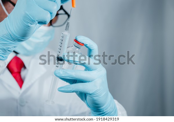 Doctor\
or scientist wearing antivirus clothing In the laboratory, research\
laboratories are studying and developing a medical vaccine,\
COVID-19, holding a syringe with a liquid\
vaccine.