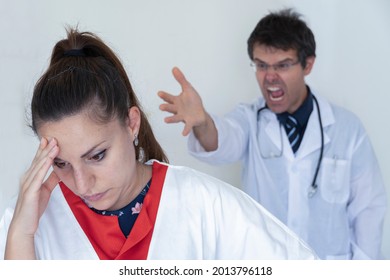 Doctor screams and yells at the poor scared and disconsolate nurse. Concept of bullying on nurses in healthcare