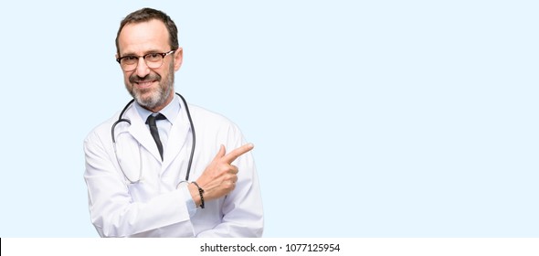 Doctor senior man, medical professional pointing away side with finger isolated over blue background - Shutterstock ID 1077125954