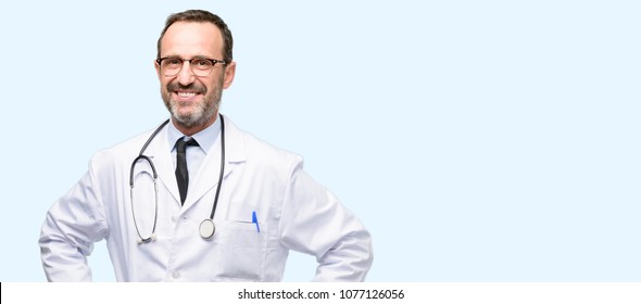 Doctor senior man, medical professional confident and happy with a big natural smile laughing isolated over blue background - Shutterstock ID 1077126056