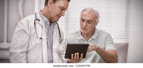 Doctor And Senior Patient Using Digital Tablet In Clinic