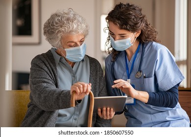 Doctor and senior woman going through medical record on digital tablet during home visit wearing face mask. Old woman with nurse with surgical mask and using digital tablet during coronavirus pandemic - Shutterstock ID 1850607550