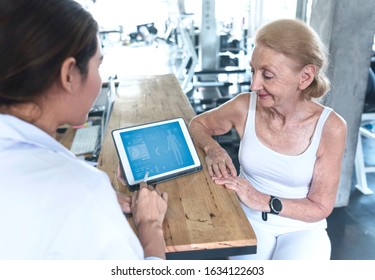 Doctor With Senior Woman In Rehabilitation Center Check Health Care And Showing Data Something On Tablet.