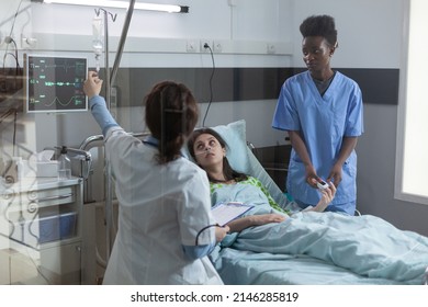 Doctor Setting Up Central Line Catether With Iv Drip Medication To Patient While Nurse Is Putting Pulse Oximeter On Finger. Woman In Hospital Bed Looking At Doctor Giving Her Intravenous Antibiotics.