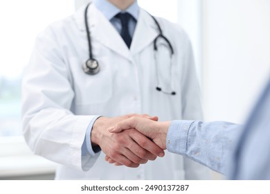 Doctor shaking hands with patient in clinic, closeup - Powered by Shutterstock