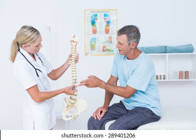 Doctor Showing Anatomical Spine To Her Patient In Medical Office