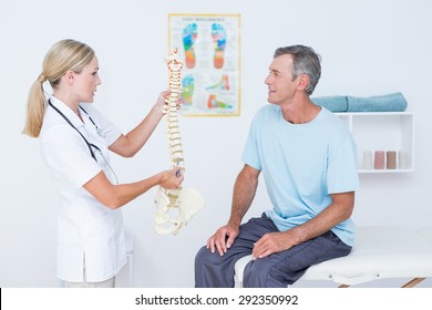Doctor Showing Anatomical Spine To Her Patient In Medical Office
