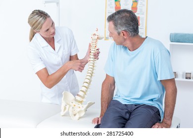 Doctor showing her patient a spine model in medical office - Powered by Shutterstock