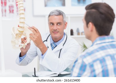 Doctor showing his patient a spine model in medical office - Powered by Shutterstock