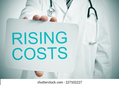 A Doctor Showing A Signboard With The Word Rising Costs Written In It