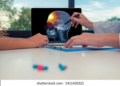 Doctor showing a x-ray of skull with pain in the front of the brain on a laptop to a woman patient.