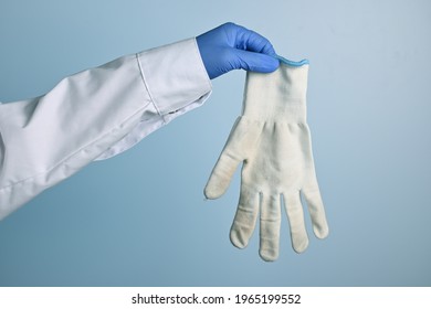 Doctor Shows Dirty White Cotton Glove. Medic Hand With Unhygienic Protective Fabric Glove. Doctor Hand Wearing A Blue Nitrile Glove Holds Another Fabric. Blue Gradient Background.