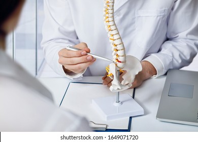 The doctor shows an intervertebral hernia on the spine at the table. - Powered by Shutterstock