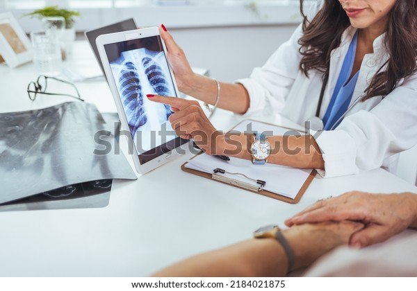 Doctor\
shows results to old patient x-ray of the lungs, smoking cigarettes\
problem. Doctor explaining lungs x-ray on Tablet PC screen to young\
patient. Doctor showing female patient x-ray shot\
