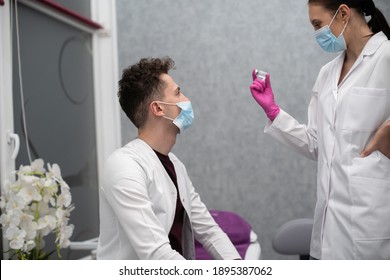 The Doctor Shows The Trainee A Set Of A Syringe And A Vial With The Medicine And Explains How To Handle It. The New Vaccine Formula Is COVID19. A Sterile Doctor's Office In A Private Clinic.