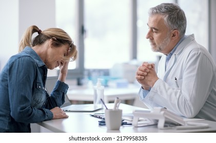 Doctor sitting at desk and giving a bad prognosis to his patient, she is sad and hopeless - Shutterstock ID 2179958335