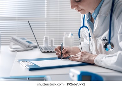 Doctor sitting at desk and writing a prescription for her patient