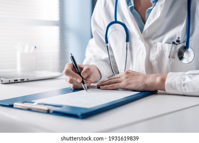 Doctor sitting at desk and writing a prescription for her patient - Powered by Shutterstock