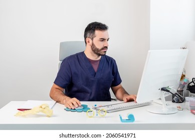 Doctor Sitting In His Office Reviewing Medical Reports On The Computer