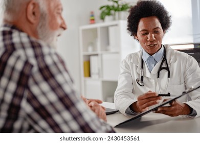 Doctor specialist consulting a patient in a doctor's office at a clinic. Female doctor is talking with a male elderly patient. - Powered by Shutterstock