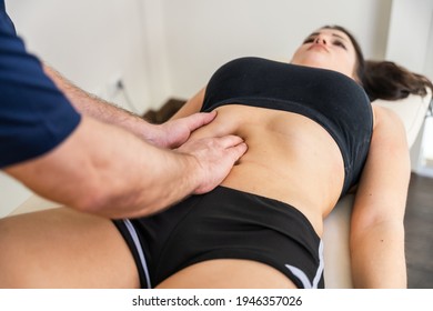 Doctor specialized in osteopathy in the medical clinic performs manipulations and visceral massages to the young woman patient with her hands acting on the abdomen for an intestinal blockage