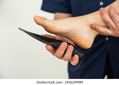 Doctor specializing in plantar posturology in his medical office tests the orthopedic device insoles on the patient's foot - Flatfoot treatment in podiatry clinic - Shutterstock ID 1936199989