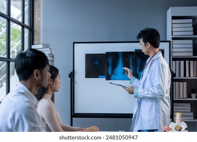 A doctor is standing in front of a white board with a picture of a skeleton on it. He is pointing to the picture and talking to a group of people. Scene is informative and educational - Powered by Shutterstock