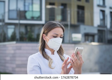 Doctor Standing Outside Hospital Using Cellular Phone For Message Send