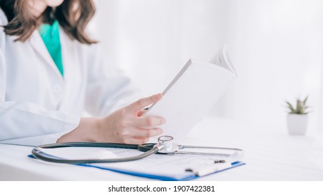 A Doctor With Stethoscope And Chart Is Reading A Book On A White Background. 